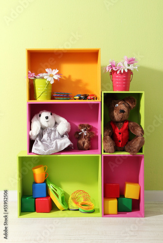 Photo: Bright shelves of different colors with toys on wall background Bright shelves of different colors with toys on wall background