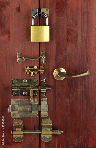 Photo: Metal bolts, latches and hooks in wooden door close-up Metal bolts, latches and hooks in wooden door close-up