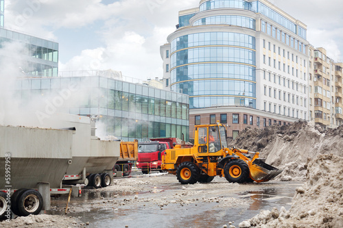 Photo: Orange bulldozer loads wet snow to trucks for snow melting Orange bulldozer loads wet snow to trucks for snow melting