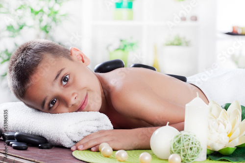 Photo: young boy relaxing in spa. stone massage. young boy relaxing in spa. stone massage.