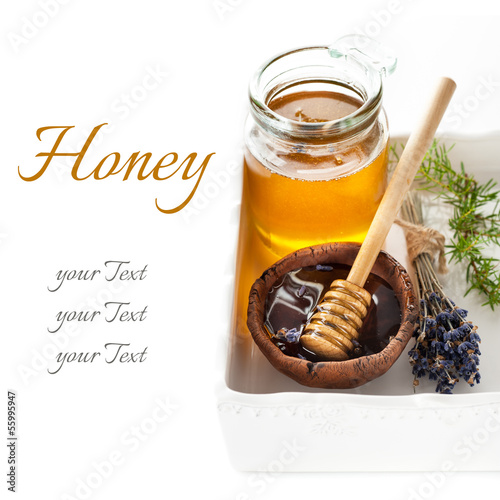 Photo: Glass jars of honey and a spoon of honey on white background Glass jars of honey and a spoon of honey on white background