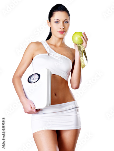 Photo: Healthy woman stands with the scales and green apple. Healthy woman stands with the scales and green apple.