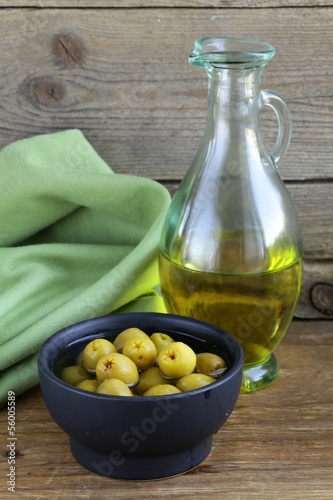 Photo: marinated green olives and a bottle of oil on wooden table marinated green olives and a bottle of oil on wooden table