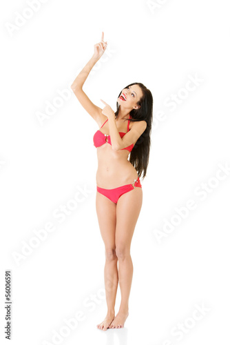 Photo: Young beautiful woman in bikini pointing on copy space Young beautiful woman in bikini pointing on copy space