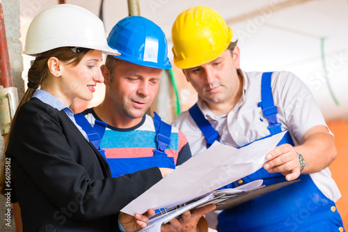 Photo: Work Team on construction site controlling floor plan Work Team on construction site controlling floor plan