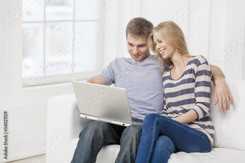 Photo: young caucasian couple sitting on couch young caucasian couple sitting on couch