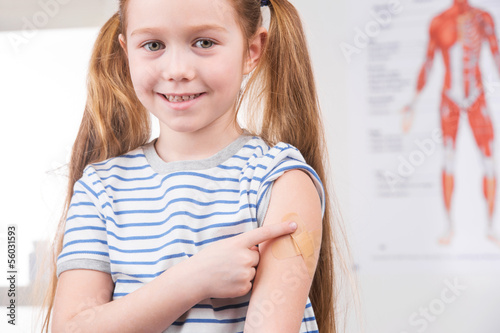 Photo: Vaccination. Cheerful little girl holding finger on the arm and Vaccination. Cheerful little girl holding finger on the arm and