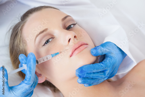 Photo: Surgeon making injection above lips on cute woman lying Surgeon making injection above lips on cute woman lying