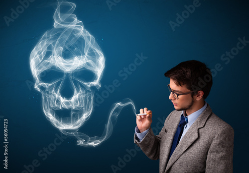 Photo: Young man smoking dangerous cigarette with toxic skull smoke Young man smoking dangerous cigarette with toxic skull smoke