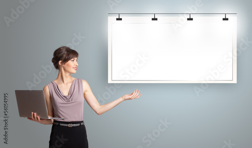 Photo: young woman holding a laptop and presenting modern copy space young woman holding a laptop and presenting modern copy space