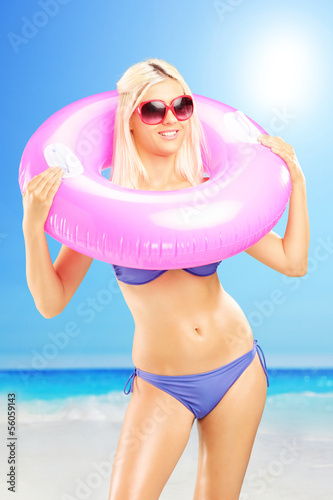 Photo: Blond female in bikini holding a swimming ring on a beach Blond female in bikini holding a swimming ring on a beach