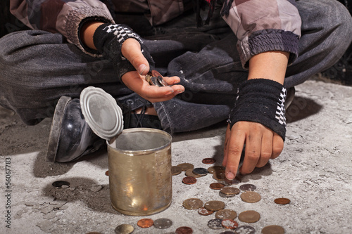 Photo: Beggar child counting coins sitting on damaged concrete floor Beggar child counting coins sitting on damaged concrete floor