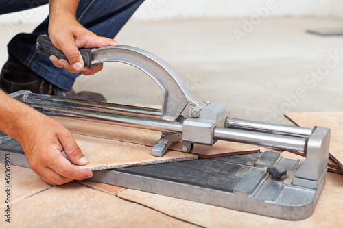 Photo: Worker cutting floor tiles with manual cutter Worker cutting floor tiles with manual cutter