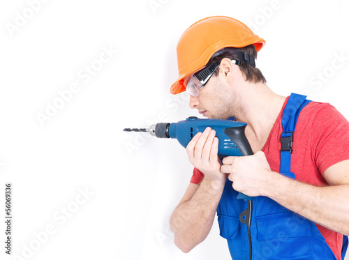 Photo: A man drilling a hole in the wall. A man drilling a hole in the wall.