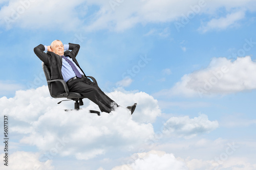 Photo: Mature businessman resting in armchair and floating on a cloud Mature businessman resting in armchair and floating on a cloud