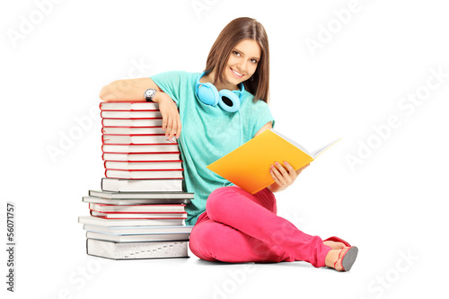 Photo: Smiling female student with headphones posing near many books Smiling female student with headphones posing near many books