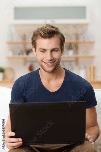 Photo: mann sitzt mit laptop auf dem sofa mann sitzt mit laptop auf dem sofa