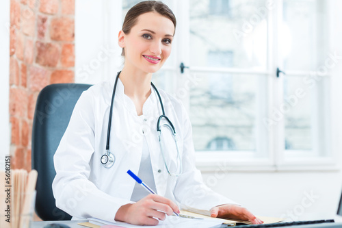 Photo: Female doctor writing in document Female doctor writing in document