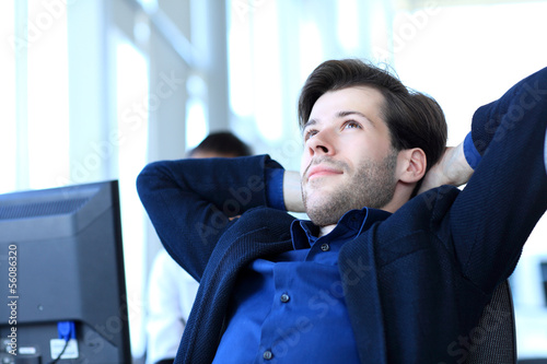 Photo: Satisfied businessman relaxing in his office Satisfied businessman relaxing in his office