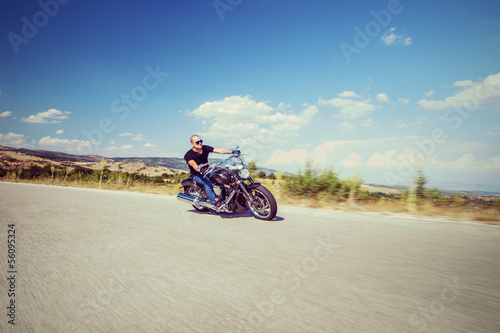 Photo: Young biker riding a motorcycle on an open road Young biker riding a motorcycle on an open road