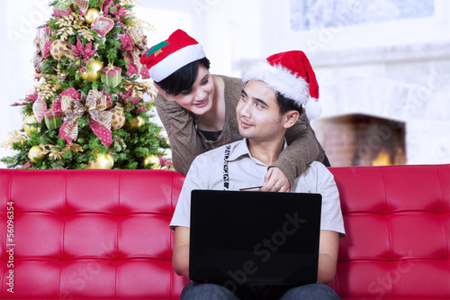 Photo: Couple buying christmas gift online at home Couple buying christmas gift online at home