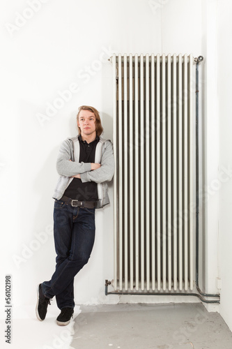Photo: portrait of young man.leaning on the radiator portrait of young man.leaning on the radiator