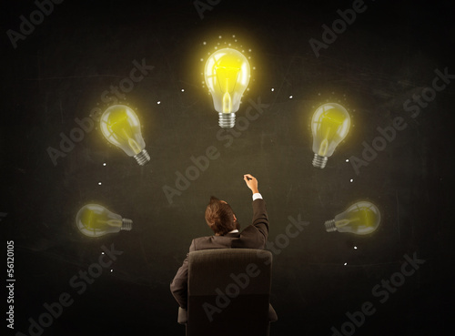 Photo: Businessman sitting with lightbulbs over his head Businessman sitting with lightbulbs over his head