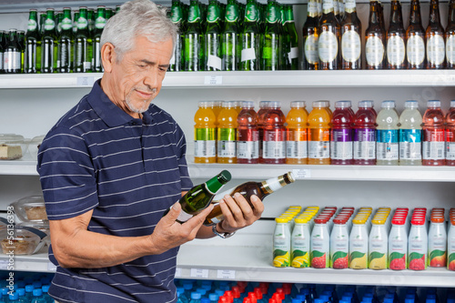 Photo: Senior Man Comparing Beer Bottles Senior Man Comparing Beer Bottles