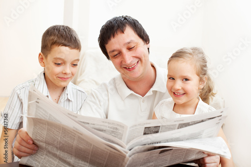 Photo: Family reading a newspaper Family reading a newspaper