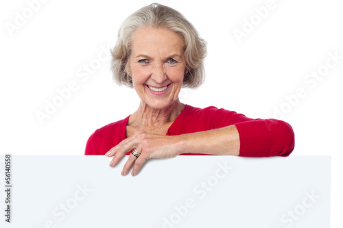 Photo: Aged woman standing behind blank billboard Aged woman standing behind blank billboard