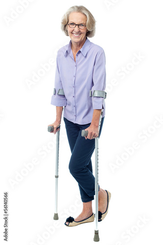 Photo: Bespectacled old woman walking with crutches Bespectacled old woman walking with crutches