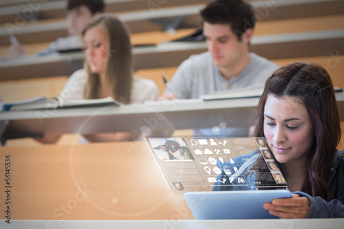Photo: Focused pretty student working on her futuristic tablet Focused pretty student working on her futuristic tablet