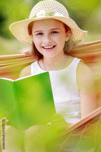 Photo: Girl with book resting on a hammock in the garden Girl with book resting on a hammock in the garden
