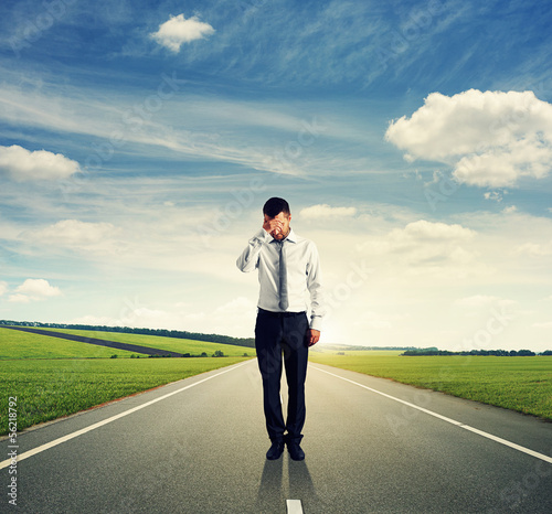 Photo: man standing on the road and looking down man standing on the road and looking down