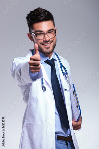 Photo: young doctor shows thumb up and smiles young doctor shows thumb up and smiles