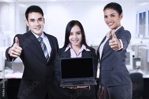 Photo: Young business people showing blank screen on laptop Young business people showing blank screen on laptop