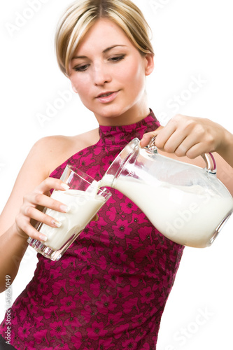 Photo: Beautiful woman pour out milk into glass Beautiful woman pour out milk into glass