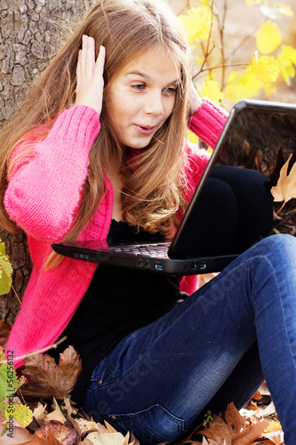 Photo: Pretty girl in autumn park with laptop Pretty girl in autumn park with laptop