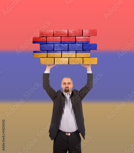 Photo: Businessman holding a large piece of a brick wall Businessman holding a large piece of a brick wall