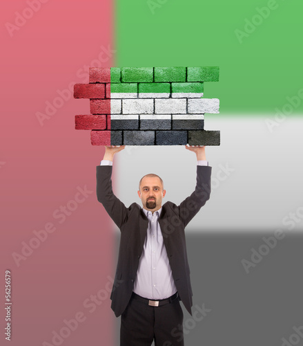 Photo: Businessman holding a large piece of a brick wall Businessman holding a large piece of a brick wall
