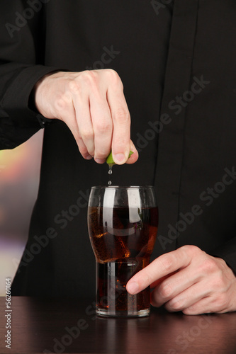 Photo: Bartender making cocktail on bright background, close-up Bartender making cocktail on bright background, close-up