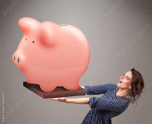 Photo: Young girl holding a huge savings piggy bank Young girl holding a huge savings piggy bank