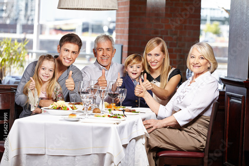 Photo: Familie im Restaurant hält Daumen hoch Familie im Restaurant hält Daumen hoch