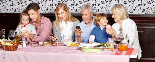 Photo: Familie beim Essen schaut auf Smartphone Familie beim Essen schaut auf Smartphone