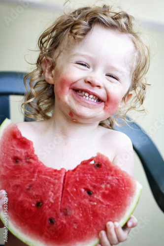 Photo: Little girl laughing and eating melon Little girl laughing and eating melon