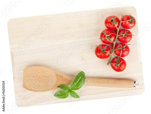 Photo: Cooking utensil and tomato with basil over cutting board Cooking utensil and tomato with basil over cutting board