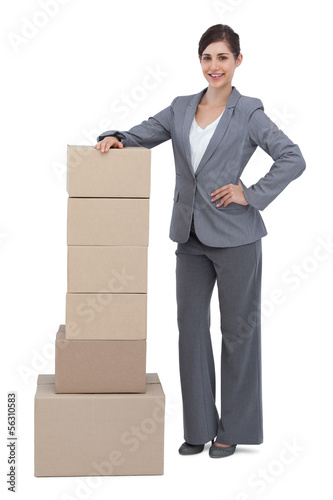 Photo: Serious businesswoman with cardboard boxes on her side Serious businesswoman with cardboard boxes on her side