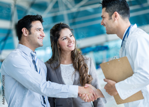 Photo: Family doctor handshaking a couple Family doctor handshaking a couple