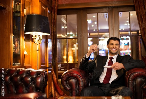 Photo: Handsome smiling brunette sitting with a cup of coffee Handsome smiling brunette sitting with a cup of coffee