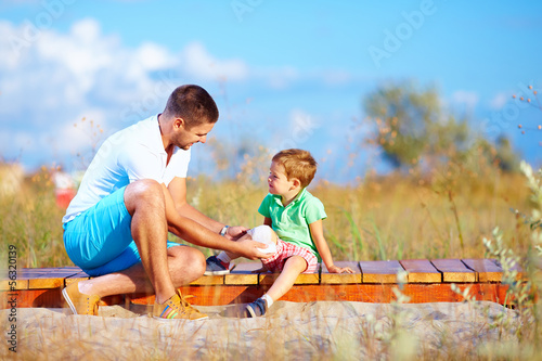 Photo: father bandaging injured leg of kid father bandaging injured leg of kid